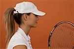 A female tennis player wearing a cap and holding a racket