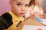 Boy sitting at a table, looking at camera