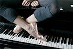 A female ballet dancer sitting on a piano
