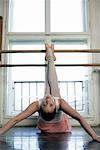 A female ballet dancer stretching legs up, lying on the floor