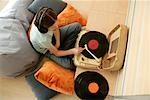 Girl listening to music of a record player by earphones