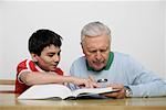 Boy showing grandfather something in a book, fully_released