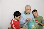 Grandfather showing two boys something at a globe, fully_released