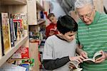 Grandfather and boy reading a book in front of a bookshelf, fully_released