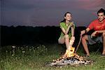 Jeune couple assis devant un feu de camp