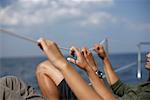 Couple holding on a safety line on a sailboat