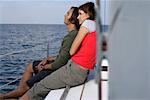 Couple sitting at border of a sailboat, looking over the sea