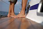 Couple on deck of a sailboat, focus on feet