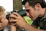 Son looking at father through binoculars