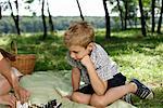 Father and son playing chess on a blanket