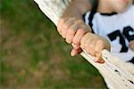 Father and son lying in hammock, focus on hands