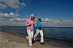 Two mature women jogging at Baltic Sea beach