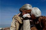 Two mature women embracing each other, one woman crying