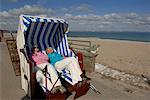 Two mature women lying in a beach chair and sunbathing