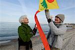 Two mature women flying a kite at Baltic Sea beach