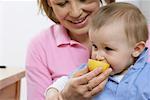 Mother feeding son with a lemon