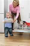 Son and mother emptying a dishwasher