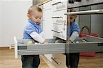 Baby boy emptying a kitchen drawer