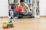 Father with two sons trying to using a mobile phone and a laptop