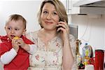 Mother carrying son on the arm while she using a phone, baby boy holding a lemon