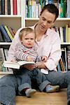 Father and son sitting in front of a shelf, baby boy looking angry