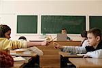 Zwei SchülerInnen kämpfen mit Stiften in einem Klassenzimmer