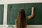 Teenage girl writing on blackboard