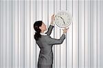 Businesswoman Hanging Clock on Wall