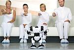 Porträt der Familie auf dem Sofa sitzend, mit Fernbedienungen auf Roboter