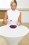 Woman Sitting at Table, Eating Meal of Pills