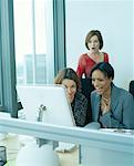 Women Giggling in Front of Computer while Colleague is Watching