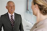 Elderly manager smiling, while talking to blond business woman