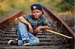Boy With Skateboard Sitting On Train Tracks