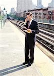 Man with Cellular Phone and Newspaper on Train Platform