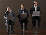 Three Businessmen Using Laptop Computers