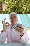 Man Holding Playing Cards and Showing OK Sign