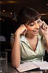 Femme avec le Journal et le téléphone cellulaire au Bar