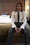 Homme d'affaires assis sur le bord du lit de la chambre d'hôtel