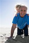 Grandfather playing with granddaughter on beach