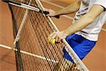 Mid section view of a man leaning against a tennis net