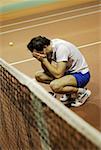 Side profile of a mid adult man crouching on a tennis court