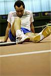 Mid homme adult assis sur un court de tennis