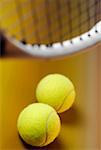 Close-up of two tennis balls with a tennis racket