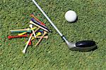 Close-up of a golf club with a golf ball and tees on the grass