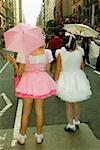 Vue arrière des deux femmes, debout sur la route tenant des parapluies