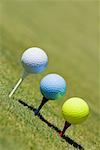Close-up of three golf balls on three tees on a golf course