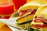 Close-up of roast beef and cheese sandwich near a glass of fruit juice