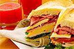 Close-up of roast beef and cheese sandwiches near two glasses of fruit juice