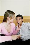 Close-up of a young woman feeding chocolates to a mid adult man