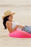 Side profile of young woman lying on an inflatable ring at the beach